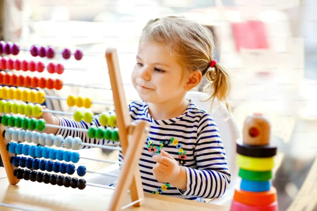 Preschool children and toddlers learning through sensory play activities with the support of a teacher and caregiver.