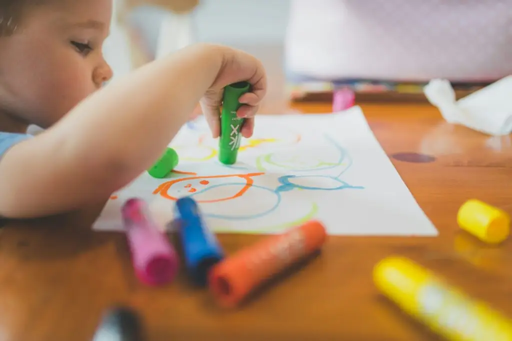 A toddler and preschooler engaging in play-based learning activities, guided by a parent and teacher in an early childhood classroom.