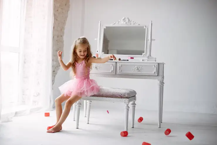 A preschool girl playing with a vanity role-play set, pretending to get ready for a party with toy accessories.